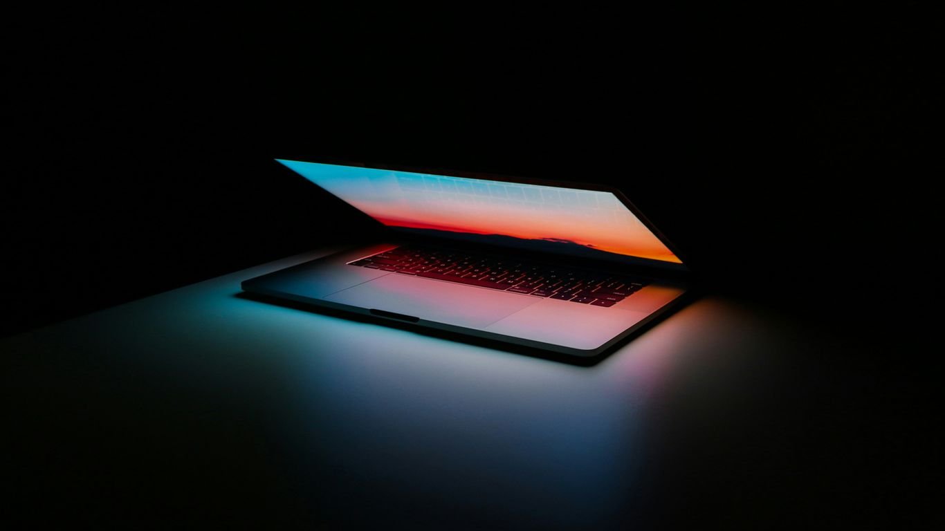 Laptop half open in a dark room, screen glowing